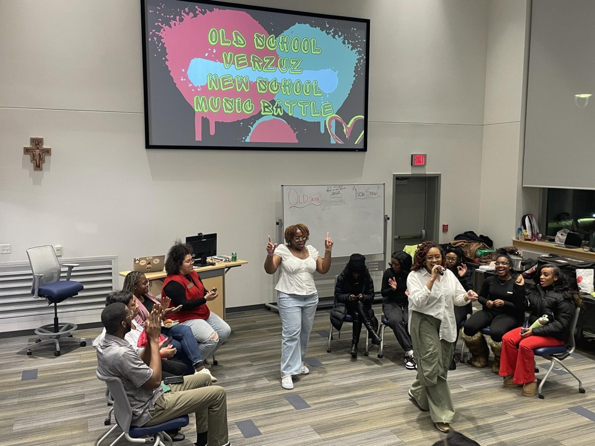  Cassie Mitchel (left white shirt) and Angelica Smith (right white shirt) explaining the Verzuz Competition. Team Old School sitting on the left and Team New School sitting on the right.